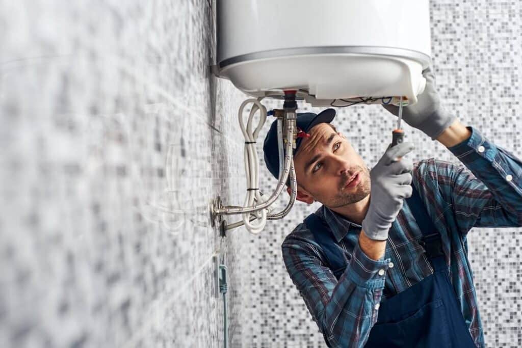 Technician performing water heater installation in a Scarborough - ME basement with carefully aligned piping