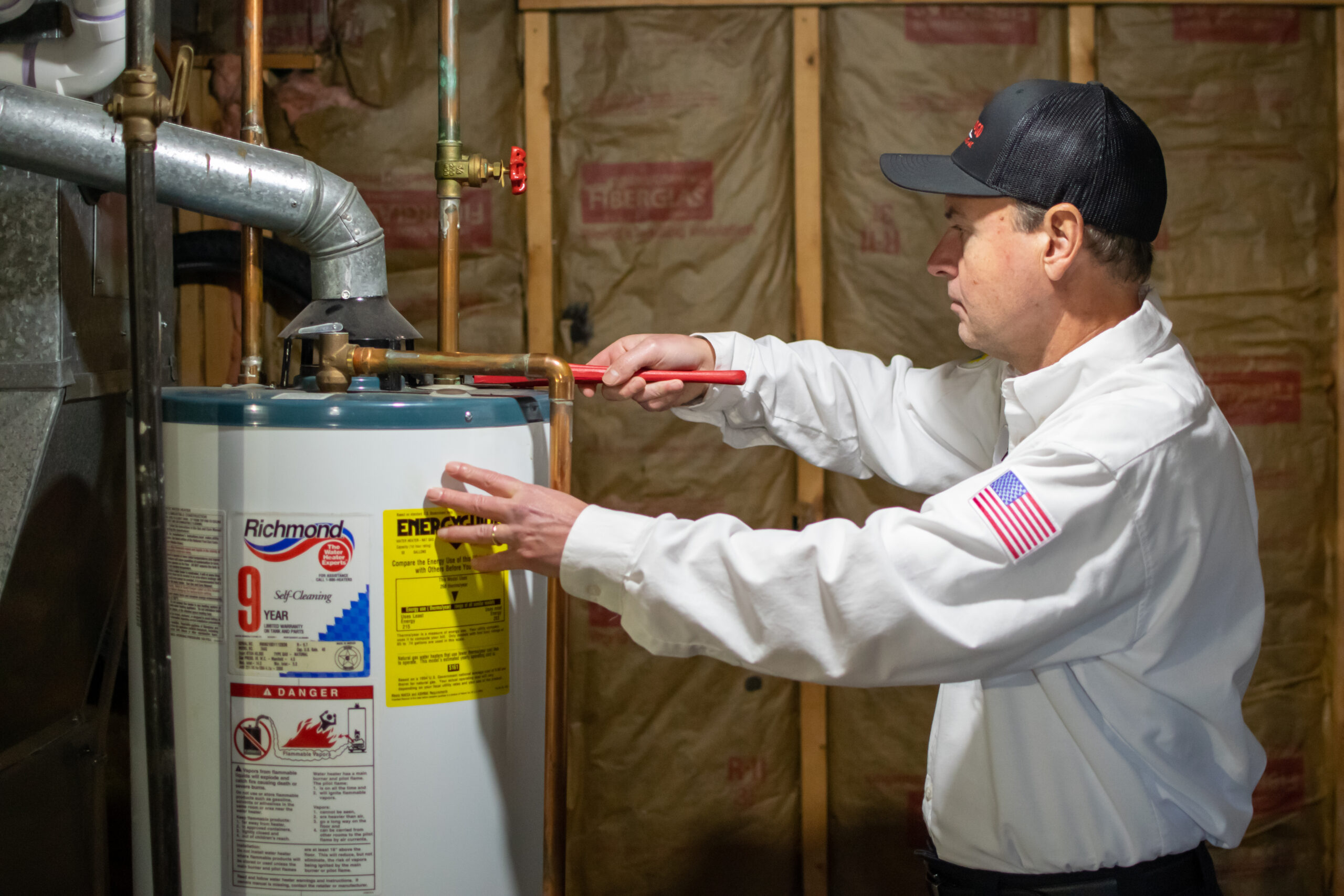 Technician performing water heater installation in a Scarborough - ME basement with carefully aligned piping