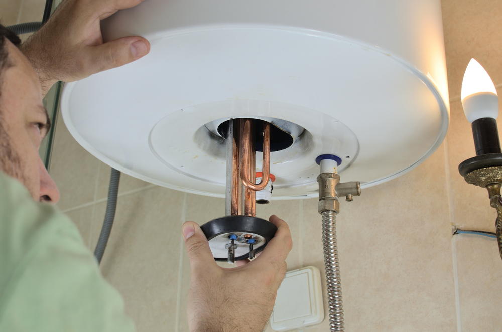 Technician performing water heater maintenance in a Scarborough - ME basement while checking system controls