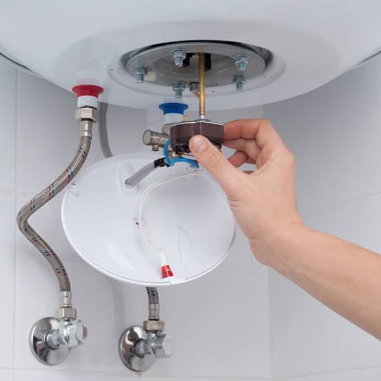 Technician performing water heater maintenance in a Scarborough - ME basement while checking system controls