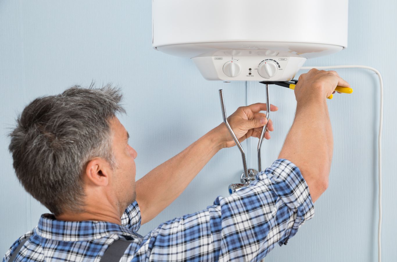 Technician checking an electric tank, illustrating Water Heater Installation in York, ME by Wanda’s Water Heaters.