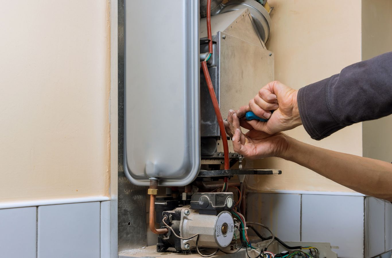 Hands adjusting a wall heater, illustrating Water Heater Installation in York County, ME by Wanda’s Water Heaters.