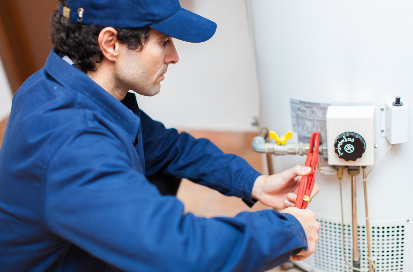 Technician tightening tank pipes, illustrating Water Heater Installation in Portland, ME by Wanda’s Water Heaters.